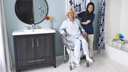 MC6000 roll-in chair over a toilet, with the tub frame standing beside the bathtub