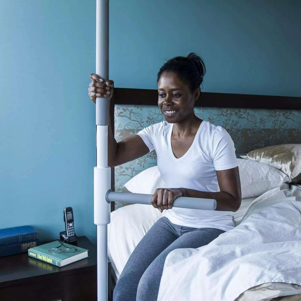 Woman sitting on the edge of her bed, one hand on the pole and one on the SuperBar beside her